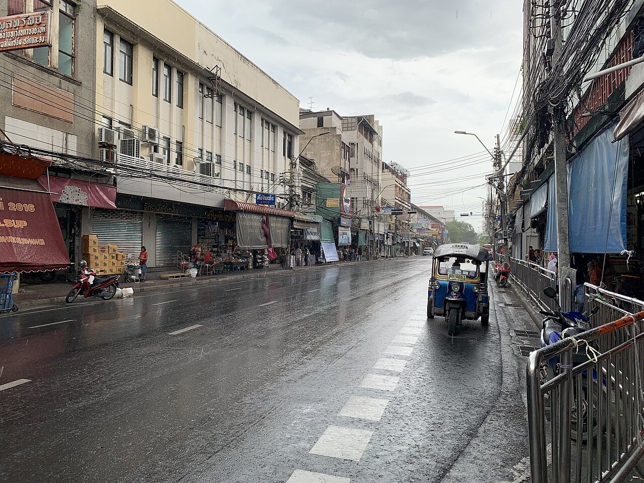 ถนนกรุงเทพฯ เปียกฝน มีรถตุ๊กตุ๊กและผู้คนกางร่ม
